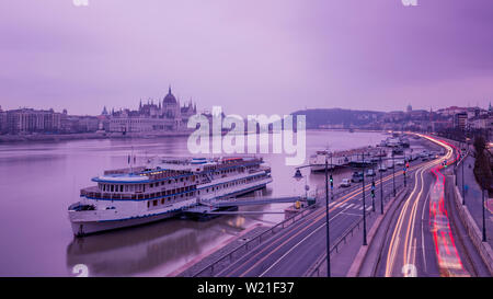 Stadtbild von Budapest mit dem Parlament und Donau. Lila Farben, Himmel, Wasser und Licht tracks von Autos widerspiegelt. Stockfoto