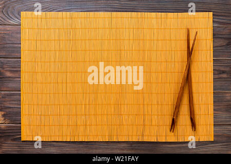 Zwei Sushi mit Stäbchen mit gelben leer Bambus matte oder Holz auf Holz- Hintergrund Draufsicht mit kopieren. Leer asiatische Lebensmittel Hintergrund. Stockfoto