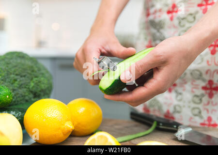 Frau Kochen gesund essen in Ihre Küche, sie ist Peeling ein frische Gurke auf dem Schneidebrett Stockfoto