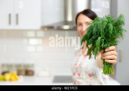 Lächelnde Frau mit frischen organischen Dill Kräuter. Frau bereitet leckeres und gesundes Essen in der Küche zu Hause. Stockfoto