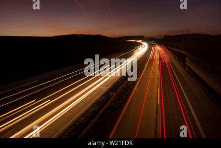 Nacht städtische Szene Bewegungen verschwommen Licht Spuren leuchten auf der dunklen Autobahn Verkehr Verkehr in die Stadt kurz nach Sonnenuntergang. Lange Belichtung Stockfoto