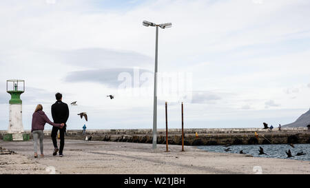 Ein Amouröses paar Spaziergänge entlang der Hafenmauer der Kalk Bay auf sein 100-jähriges Jubiläum in Südafrika. Stockfoto