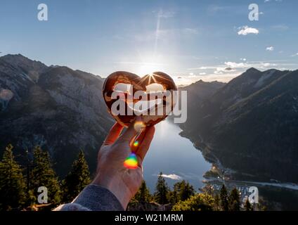 Hand, die Bayerische brezel vor Alpenpanorama Blick von Schonjochl, Plansee, Tirol, Österreich Stockfoto