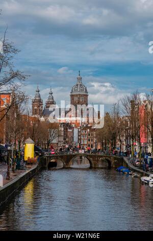 Blick von einer Brücke an Oudezijds Voorburgwal zum Kanal und die Sint Nicolaaskerk, Sankt Nikolas-Kirche, Amsterdam, Nordholland, Niederlande Stockfoto