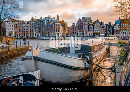 Blick auf die Amstel im Abendlicht, Kanal mit Boot und historische Häuser, Amsterdam, Nordholland, Niederlande Stockfoto