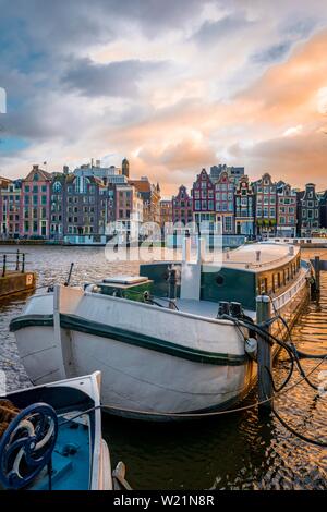 Blick auf die Amstel im Abendlicht, Kanal mit Boot und historische Häuser, Amsterdam, Nordholland, Niederlande Stockfoto