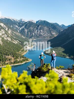 Zwei Wanderer Blick in die Ferne über den See Plansee, von Bergen, Schonjochl, Plansee, Tirol, Österreich an der Rückseite umgeben. Stockfoto