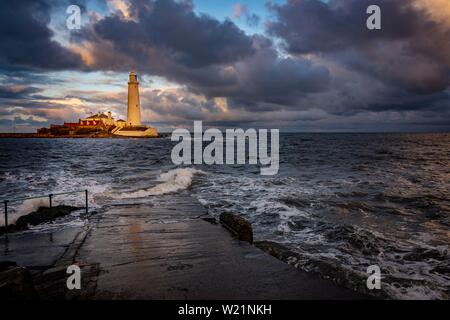 Leuchtturm, St. Mary's Leuchtturm mit gewaschen über Straße bei Flut mit dramatischen Wolken bei Sonnenuntergang, Küste von Tyne, Northumberland, Großbritannien Stockfoto