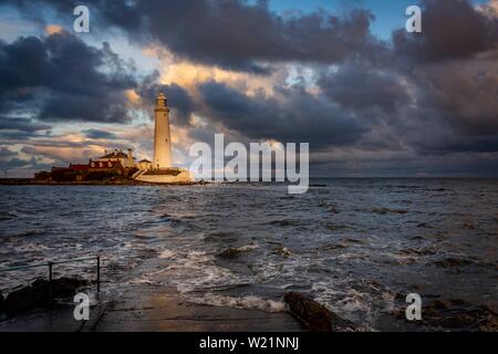 Leuchtturm, St. Mary's Leuchtturm mit gewaschen über Straße bei Flut mit dramatischen Wolken bei Sonnenuntergang, Küste von Tyne, Northumberland, Großbritannien Stockfoto