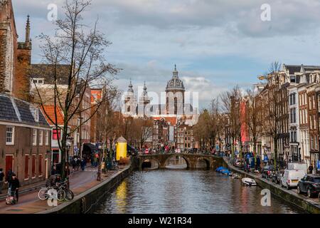 Blick von einer Brücke an Oudezijds Voorburgwal zum Kanal und die Sint Nicolaaskerk, Sankt Nikolas-Kirche, Amsterdam, Nordholland, Niederlande Stockfoto