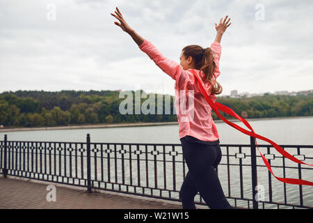 Mädchen runner beendet das Rennen mit einem roten Band. Sieger im Sport. Stockfoto