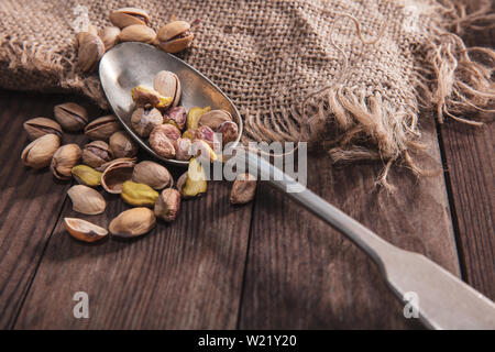 Pistazien auf einem alten Löffel und Zusammensetzung aus altem Holz und Material Stockfoto