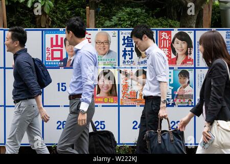 Tokio, Japan. 05. Juli, 2019. Menschen gehen vorbei an einer Plakatwand mit Postern Kandidaten für den 21. Juli Bundesrat Wahl errichtet. Die Kampagnen für das obere Haus Wahl offiziell weg am Donnerstag, 04. Juli und am 21. Juli statt. Credit: Rodrigo Reyes Marin/LBA/Alamy leben Nachrichten Stockfoto