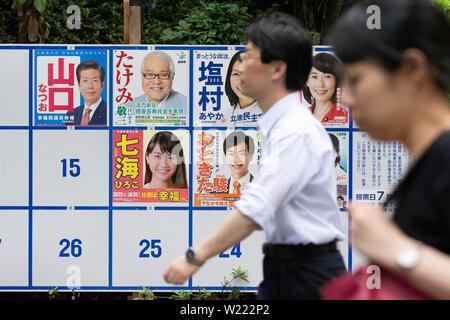 Tokio, Japan. 05. Juli, 2019. Menschen gehen vorbei an einer Plakatwand mit Postern Kandidaten für den 21. Juli Bundesrat Wahl errichtet. Die Kampagnen für das obere Haus Wahl offiziell weg am Donnerstag, 04. Juli und am 21. Juli statt. Credit: Rodrigo Reyes Marin/LBA/Alamy leben Nachrichten Stockfoto