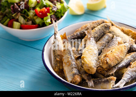 Gebratene Sardinen mit Zitrone und Salat auf Holz- Hintergrund Stockfoto