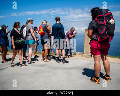 Juni 27, 2019 - Finisterra, A CoruÃ±a, Spanien - eine Gruppe von Pilgern zu sehen sind die Fotos in der KM0-Marker. Kap Finisterre ist das Ziel für die Pilger, die nach dem Besuch der St. James €™ Grab ist Santiago, ihren Weg weiter entlang der Route, die für Sie gekennzeichnet durch die Milchstraße Overhead, bis Sie nicht mehr weiter konnten. Finisterre war während der Zeit der klassischen Antike das Ende der bekannten Welt. Finisterre, oder Fisterra in Gallego, der lokalen Galizischen Dialekt bedeutet ''Land's End'' in Lateinamerika. Weiter zum Leuchtturm, gibt es die 0.0 Kilometer Marker, von wo aus die Stockfoto