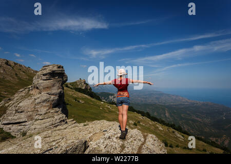 Junge schlanke Mädchen steht mit dem Rücken in einen Hut auf einem hohen Berg. Rest in der Krim. Stockfoto