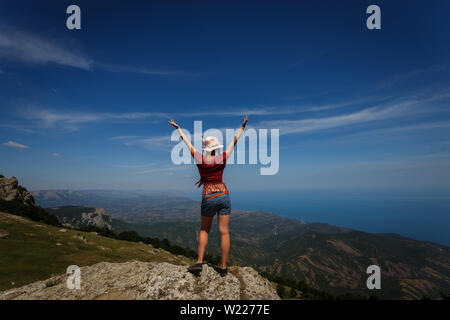 Das Konzept der Überwindung, Ruhe, Freiheit und Glück. Eine Frau mit gebräunten Beine steht oben, die Arme weit nach oben ausbreiten. Stockfoto