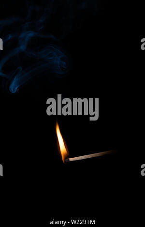Die Beleuchtung passt im Moment wenn es explodiert. Brennende Holz- Match mit blauen Rauch über schwarzen Hintergrund. Close Up. Kopieren Sie Platz. Stockfoto