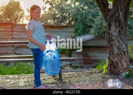 Junge Jugendmädchen recycling Plastikflaschen. Kid Freiwillige mit Müllsäcken Reinigung Park im Freien. Stockfoto