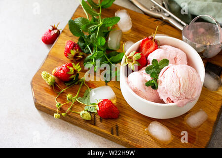 Erdbeereis in Weiß Schüssel auf einem Stein oder Schiefer Tisch. Freier Platz für Ihren Text. Stockfoto