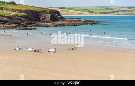 Surfer in Richtung Meer, am Strand von Polzeath in North Cornwall, UK. Am 27. Juni 2019 übernommen. Stockfoto