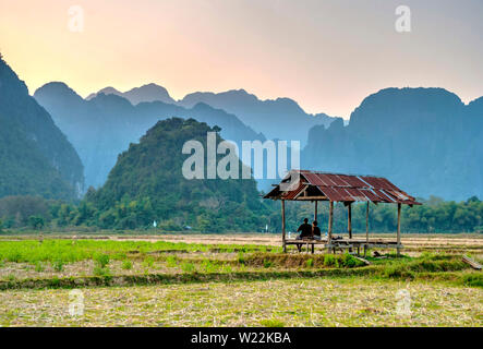 Vang Vieng, Laos - Feb 2016: Gruppe von Freunden in einem Hutt sitzen und beobachten Sie den wunderschönen Sonnenuntergang in den Bergen um Vang Vieng Stockfoto