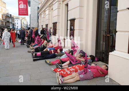 London, Greater London, UK. 2. Juli 2019. Aussterben Rebellion Aktivisten inszenierte ein sterben - in außerhalb des Royal Opera House Haupteingang halten Fahnen bei einem Protest in London Umweltschützer aus Aussterben Aufstandsbewegung ein sterben - in außerhalb des Royal Opera House in London inszeniert, um zu verlangen, dass sie Gas und Öl British Petroleum (BP) als Sponsor. Quelle: Andres Pantoja/SOPA Images/ZUMA Draht/Alamy leben Nachrichten Stockfoto