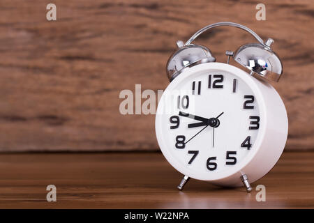 Weiß Wecker auf Holz alte Hintergrund, rote vintage Uhr auf hölzernen Tisch Stockfoto