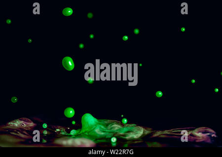 Eine bunte Farbtupfer lebendige grüne Flüssigkeit vor einem schwarzen Hintergrund isoliert Stockfoto