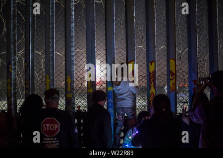 Tijuana, Mexiko. 04. Juli, 2019. Zahlreiche Menschen haben sich die Feuerwerke Leuchten hinter dem Zaun auf der mexikanischen Seite der Grenze Mauer auf US Independence Day. Menschen versammelt, um am Strand des mexikanischen Tijuana die Feiern auf der anderen Seite der Grenze zu beobachten. Credit: Omar Martinez/dpa/Alamy leben Nachrichten Stockfoto