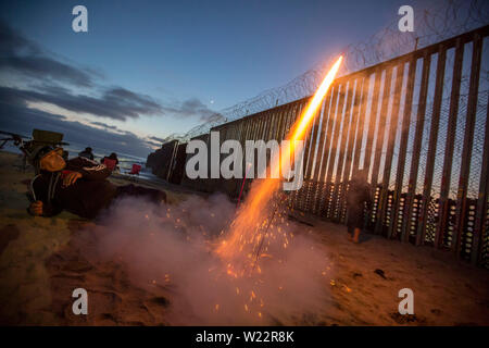 Tijuana, Mexiko. 04. Juli, 2019. Ein Mann leuchtet ein feuerwerkskörper an der Grenze zwischen Mexiko und den USA auf US Independence Day. Zahlreiche Menschen beobachtet die Feier der USA auf der mexikanischen Seite der Grenze an der Wand. Credit: Omar Martinez/dpa/Alamy leben Nachrichten Stockfoto