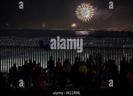 Tijuana, Mexiko. 04. Juli, 2019. Zahlreiche Menschen haben sich die Feuerwerke Leuchten hinter dem Zaun auf der mexikanischen Seite der Grenze Mauer auf US Independence Day. Menschen versammelt, um am Strand des mexikanischen Tijuana die Feiern auf der anderen Seite der Grenze zu beobachten. Credit: Omar Martinez/dpa/Alamy leben Nachrichten Stockfoto