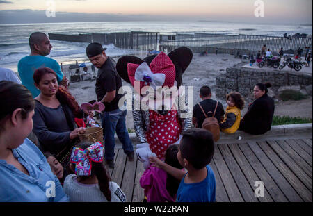 Tijuana, Mexiko. 04. Juli, 2019. 'Minnie' begrüßt die Kinder, die auf der mexikanischen Seite der Grenze Mauer für die Feiern des US Independence Day gesammelt haben. Zahlreiche Menschen haben sich die US-Feier am 4. Juli hinter dem Grenzzaun. Credit: Omar Martinez/dpa/Alamy leben Nachrichten Stockfoto