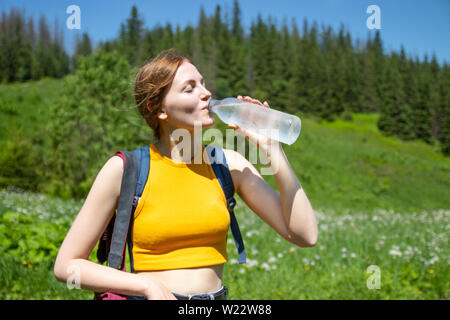 Weibliche Touristen trinken Wasser aus der Plastikflasche. Frau in den Bergen ausruhen. Reise und Tourismus Konzept Stockfoto