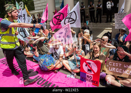 London, Großbritannien. 5. Juli, 2019. Klima Aktivisten vor dem Aussterben Rebellion mime peppersprayed durch die französische Polizei während eines Protestes außerhalb der Französischen Botschaft in Solidarität mit den Mitgliedern des Aussterbens Rebellion Frankreich, die auf kurze Distanz von der französischen Polizei peppersprayed wurden, während die Belegung der Pont de Sully in Paris für weitere Maßnahmen der Regierung und die Aufmerksamkeit der Medien auf den Klimawandel zu nennen. Credit: Mark Kerrison/Alamy leben Nachrichten Stockfoto