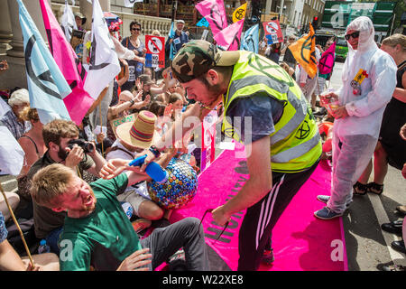 London, Großbritannien. 5. Juli, 2019. Klima Aktivisten vor dem Aussterben Rebellion mime peppersprayed durch die französische Polizei während eines Protestes außerhalb der Französischen Botschaft in Solidarität mit den Mitgliedern des Aussterbens Rebellion Frankreich, die auf kurze Distanz von der französischen Polizei peppersprayed wurden, während die Belegung der Pont de Sully in Paris für weitere Maßnahmen der Regierung und die Aufmerksamkeit der Medien auf den Klimawandel zu nennen. Credit: Mark Kerrison/Alamy leben Nachrichten Stockfoto