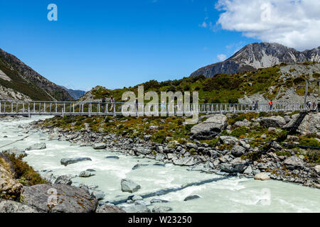 Wanderer überqueren eine Hängebrücke auf dem Hooker Valley Track, Aoraki/Mt Cook National Park, South Island, Neuseeland Stockfoto