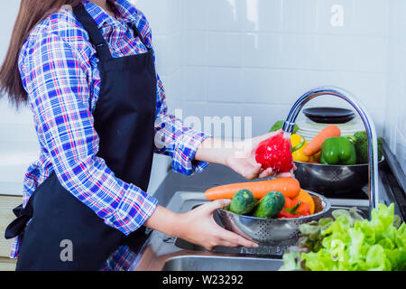 Junge Frau Waschen von Salat und Äpfel Pestizide vor dem Kochen in der Küche entfernen. Obst und Gemüse Konzept waschen. Stockfoto