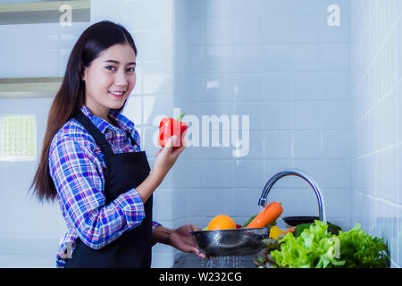 Junge Frau Waschen von Salat und Äpfel Pestizide vor dem Kochen in der Küche entfernen. Obst und Gemüse Konzept waschen. Stockfoto