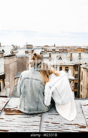 Ein junges Paar sitzt auf dem Dach bewundert und einer schönen Aussicht auf die Stadt. Romantik, Liebe und vertrauensvolle Beziehungen. Oder er Traum oder digital detox zusammen. Stockfoto