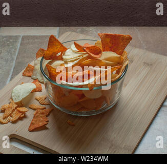 Junk Food in einer Schüssel auf einem hölzernen Schneidebrett, dunklen Essen Fotografie, Low-key-Fotografie. Stockfoto