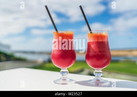 Das gesunde Essen Saft detox Konzept reinigen. Vegane Ernährung entsaften Trend. Zwei Gläser rot pflanzliche Mischung aus Karotte, Rote Bete Saft Gläser auf Outdoor Cafe oder Restaurant Tabelle auf Sommer Himmel Hintergrund. Stockfoto