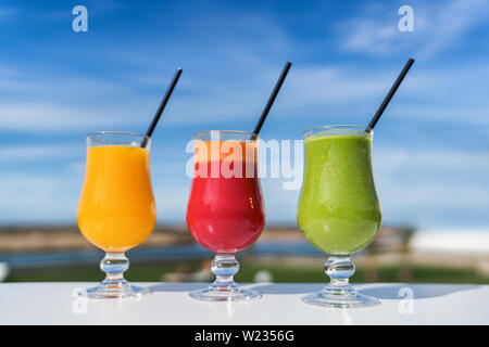 Gesunde Ernährung entsaften Diät trend Konzept reinigen - Obst- und Gemüsesaft Gläser auf Café im freien Tisch. Grüne Smoothie oder kalt gepresste Säfte. Orange, Rote Bete, Spinat und Grünen smoothie Cups. Stockfoto