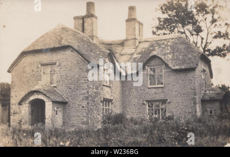 Jahrgang fotografische Postkarte mit einem freistehenden Britischen Strohdach Country House. Stockfoto