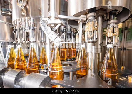 Füllen Glasflaschen mit Saft. Abfüllung von Getränken. Abfüllanlage Stockfoto