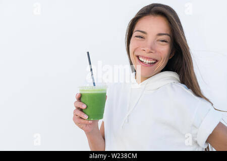 Gerne asiatische Frau trinken gesunden grünen Spinat smoothie Cup detox für Gewicht-Verlust-Diät. Junge lächelnde Fitness sportliche Mädchen mit Gemüse Saft trinken von Saft bar Gesundheit trend, weisser Hintergrund. Stockfoto