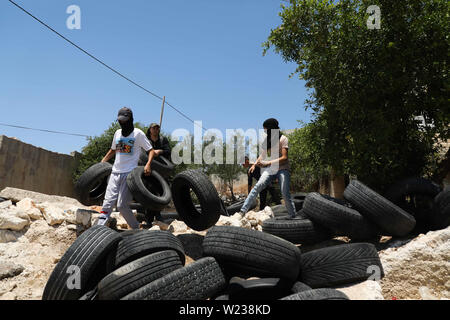 Juli 5, 2019 - Qalqilia, Palästina. 05. Juli 2019. Palästinenser Demonstranten Konfrontation mit israelischen Soldaten im Westjordanland Stadt Kafr Qaddum während ihrer wöchentlichen Freitag Protest gegen illegalen israelischen Siedlungen. Einige Palästinenser verbrannten Reifen und warfen Steine auf die israelischen Streitkräfte, die befeuerte Gas und mit Gummi überzogene Kugeln auf Demonstranten und verletzte mindestens vier von ihnen reißen. Seit Juli 2011, Bewohner von Kafr Qaddum und den benachbarten Dörfern organisieren Proteste am Freitag gegen die Verlängerung der nahe gelegenen israelischen Siedlung Qadumim, die Schließung der Palästinenser des Dorfes ma Stockfoto