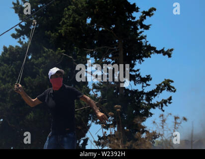 Juli 5, 2019 - Qalqilia, Palästina. 05. Juli 2019. Palästinenser Demonstranten Konfrontation mit israelischen Soldaten im Westjordanland Stadt Kafr Qaddum während ihrer wöchentlichen Freitag Protest gegen illegalen israelischen Siedlungen. Einige Palästinenser verbrannten Reifen und warfen Steine auf die israelischen Streitkräfte, die befeuerte Gas und mit Gummi überzogene Kugeln auf Demonstranten und verletzte mindestens vier von ihnen reißen. Seit Juli 2011, Bewohner von Kafr Qaddum und den benachbarten Dörfern organisieren Proteste am Freitag gegen die Verlängerung der nahe gelegenen israelischen Siedlung Qadumim, die Schließung der Palästinenser des Dorfes ma Stockfoto