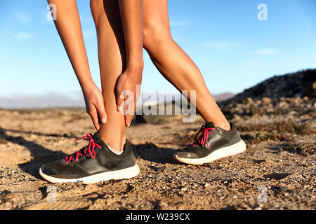 Runner Frau mit verletzten Knöchel in Schmerzen beim Marathon. Athlet Frau läuft außen mit Körperverletzung. Verstauchter Knöchel auf dem Weg im Sommer im Freien Natur laufen. Fitness bein Unfall auf cardio Workout. Stockfoto